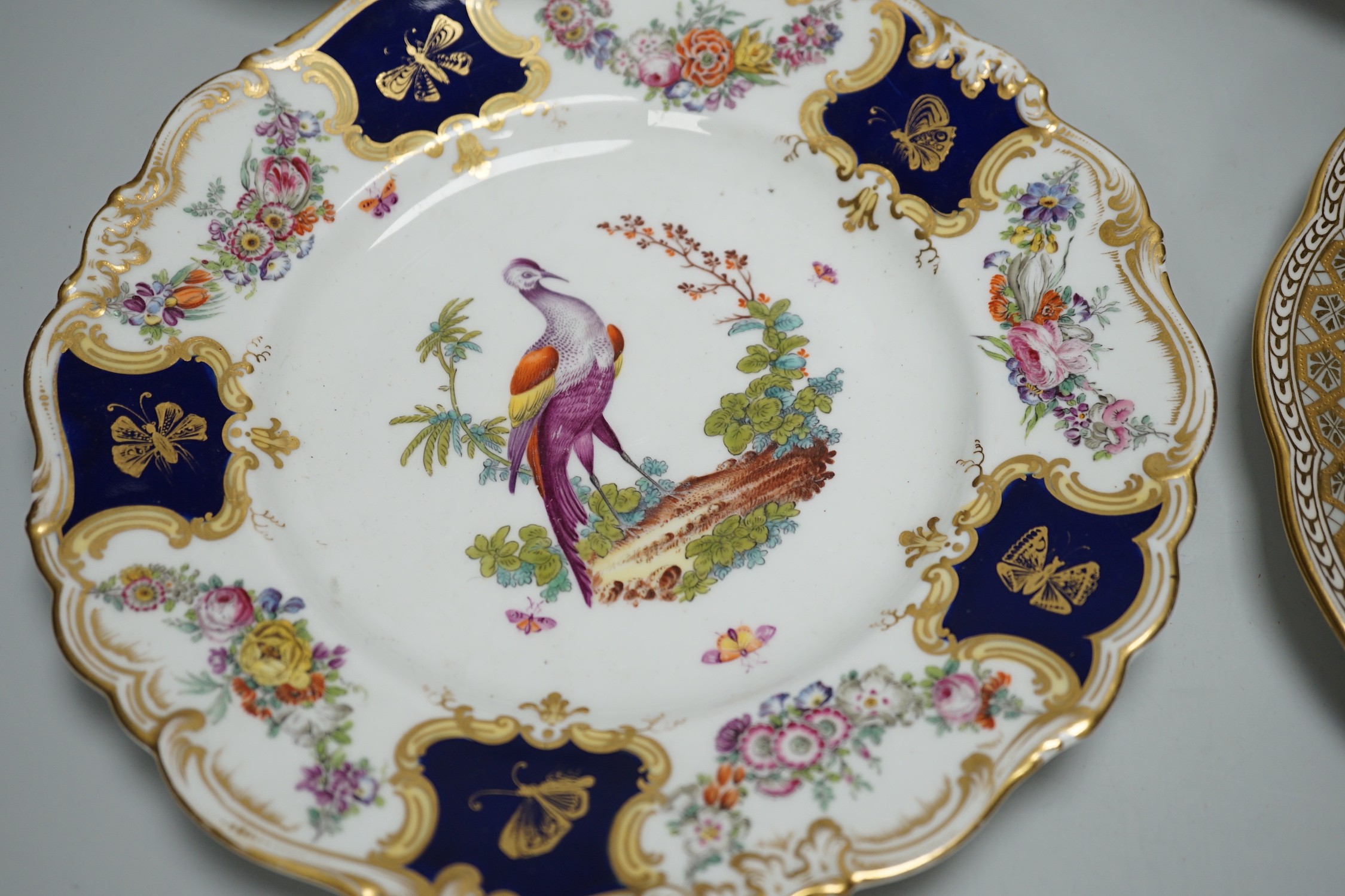 A Copeland plate decorated in Chelsea style with exotic birds on a mazarine blue ground, a similar plate probably Coalport, a Davenport plate with Windemere Lake and a Alderley pierced dish